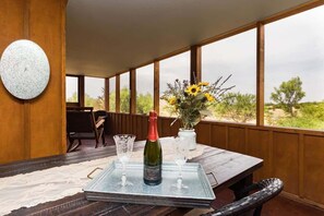 A dining area with a table set for two, featuring a bottle of wine and two glasses.