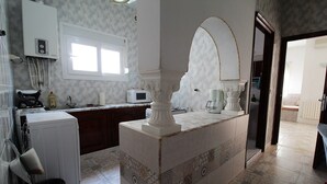 Een keuken met een ingebouwde magnetron, een wasmachine en een spoelbak.