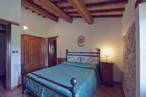 A bedroom with a bed, wooden wardrobe, stone wall, and a small bedside table with a lamp. - Authentic stone farmhouse, pool, view, bbq, wifi, bedrooms with bathroom and a/c (Resina I)