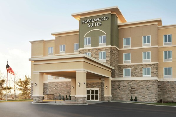 Un hôtel au design moderne, doté d’une entrée imposante avec un espace abrité et d’une enseigne indiquant « Homewood Suites ».