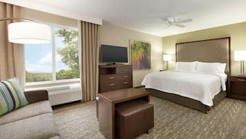 A hotel room with a bed, a TV, a desk, a chair, and a window with curtains.