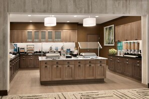 Une cuisine moderne avec des meubles en bois, un îlot central et un éclairage suspendu.