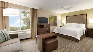 A hotel room with a bed, a TV, a desk, a chair, and a window with curtains.