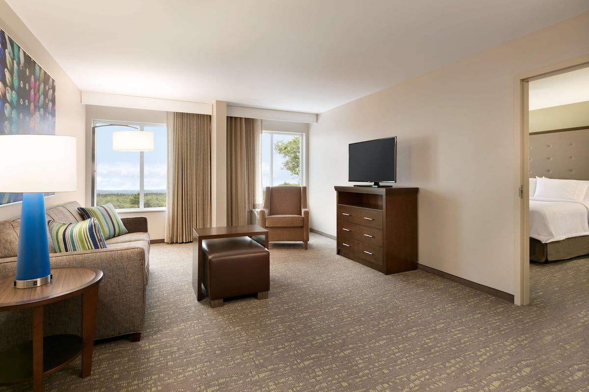 Een hotelkamer met een bank, poef, televisie en een bed.