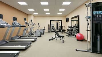 A gym with treadmills, elliptical machines, a bench press, and various weights.