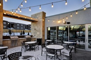 An outdoor patio area with string lights, outdoor seating, and a barbecue grill.