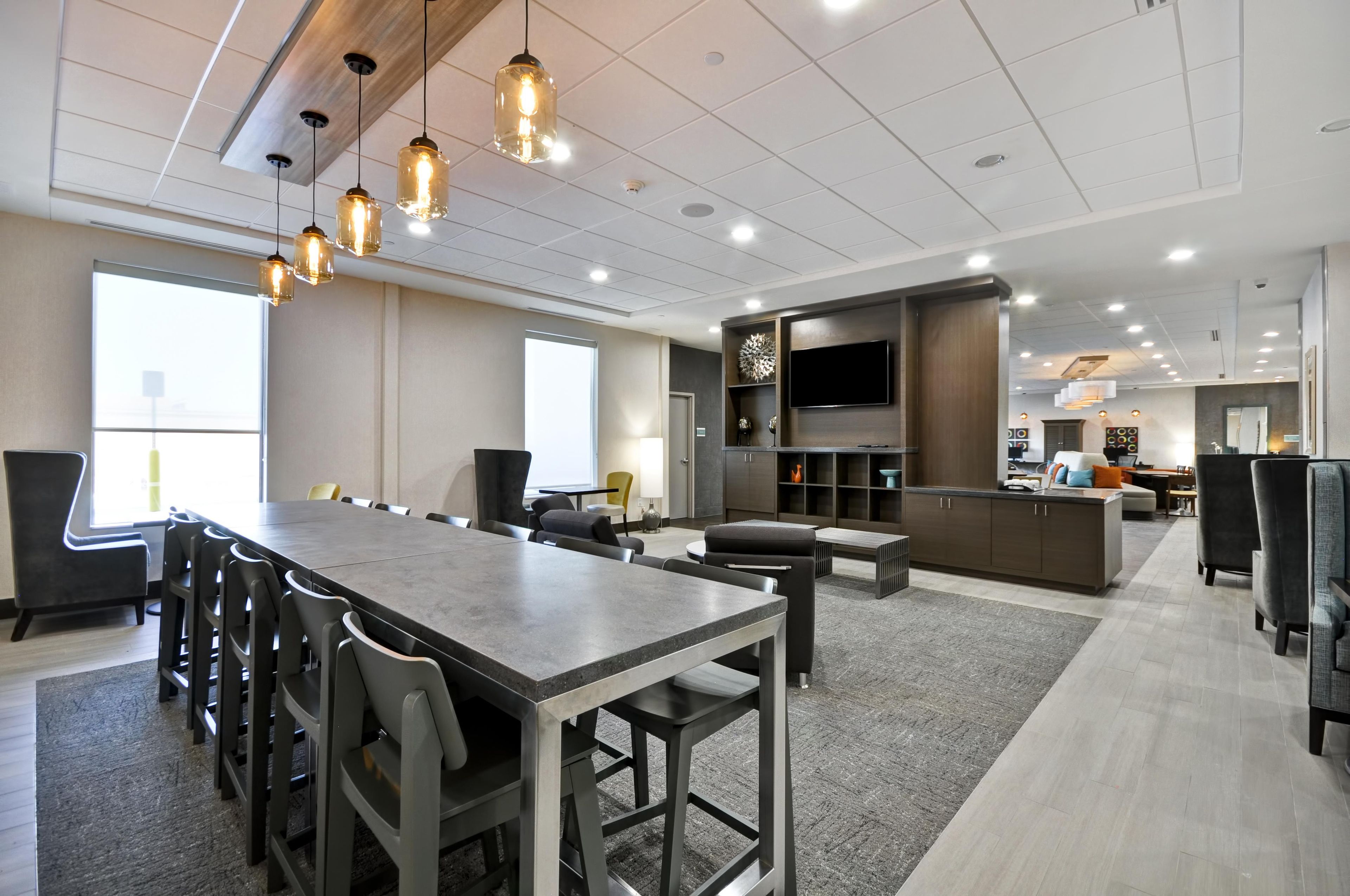 A modern conference room with a long table, chairs, and pendant lighting.