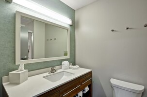 Un baño con lavamanos blanco, un espejo, toallero y un inodoro.