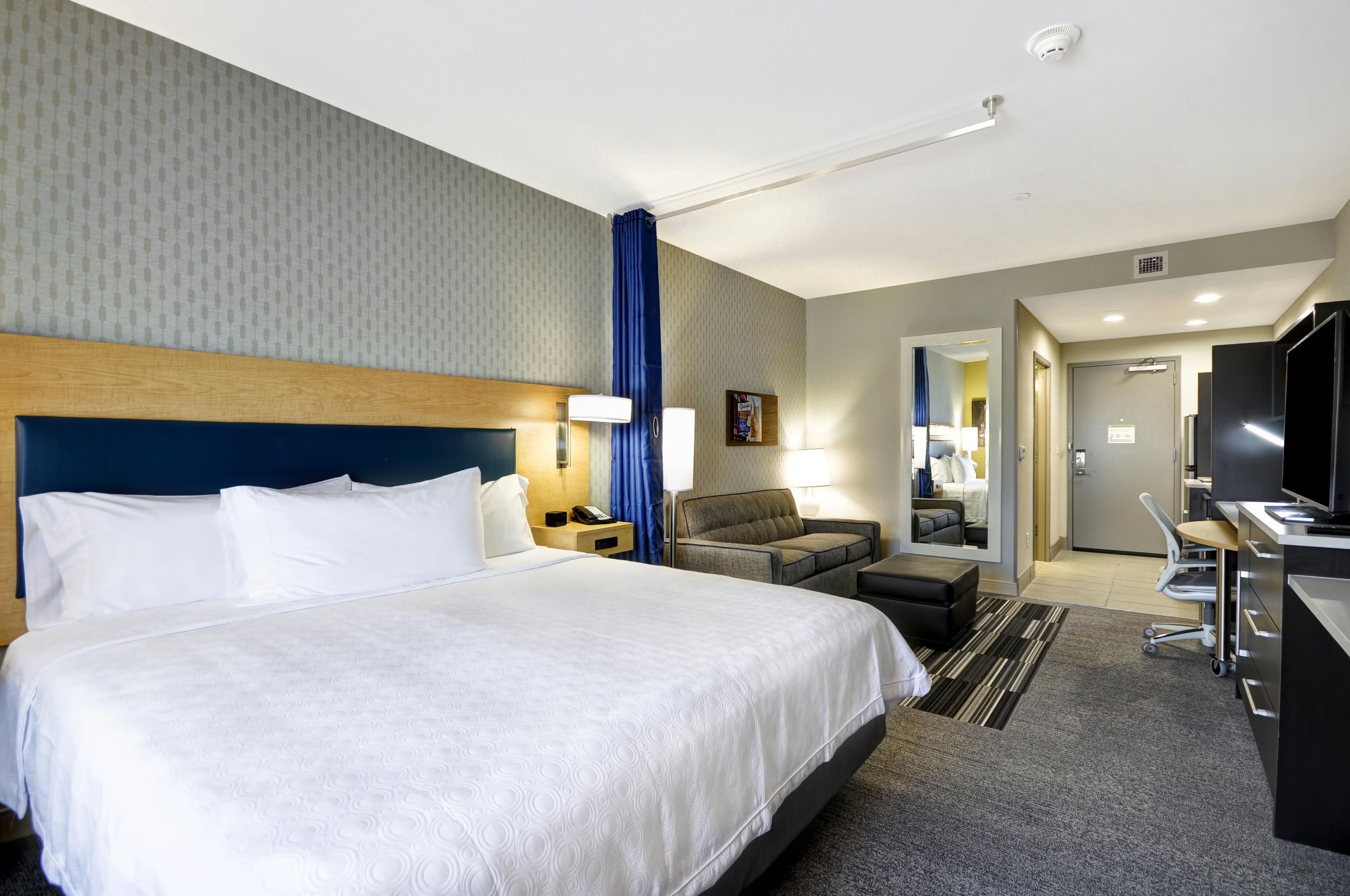 Una habitación de hotel con una cama grande, un escritorio, una silla y un televisor.