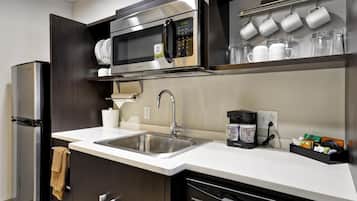 A modern kitchen with a built-in microwave, stainless steel sink, and a coffee machine.