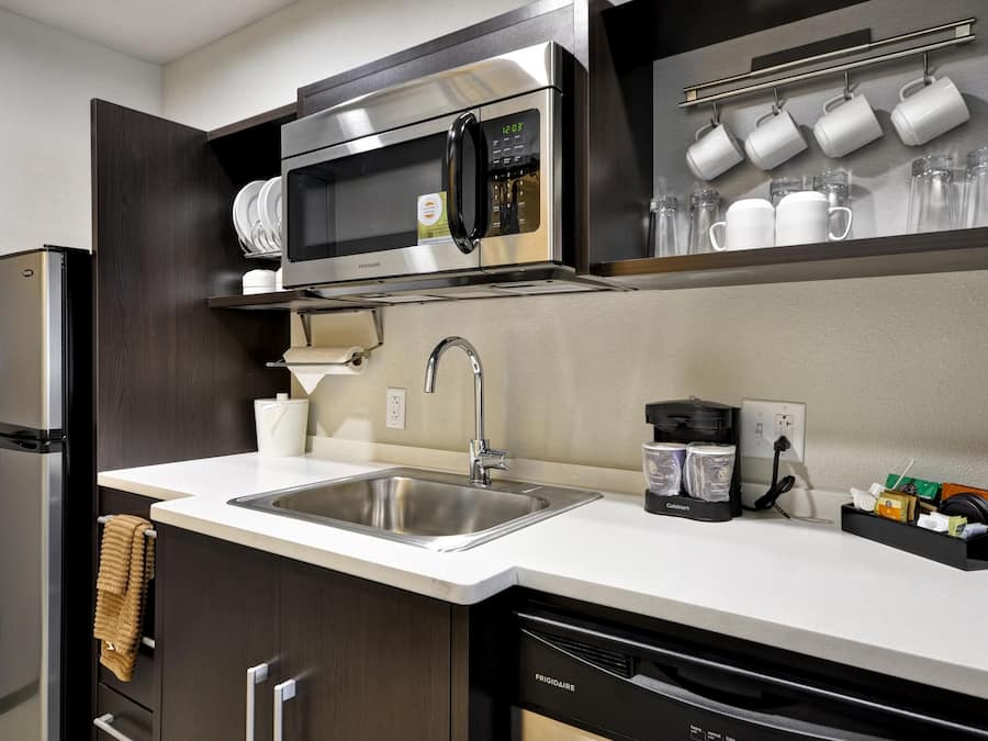 A modern kitchen with a built-in microwave, stainless steel sink, and a coffee machine.