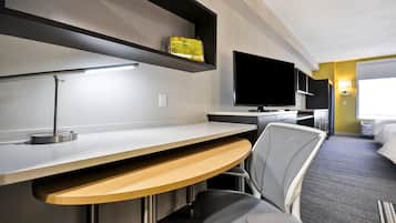 Una habitación de hotel con escritorio, silla, televisor y cama.