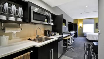 A modern kitchen with a microwave, sink, and coffee maker. There is a small dining area with a table and chairs.