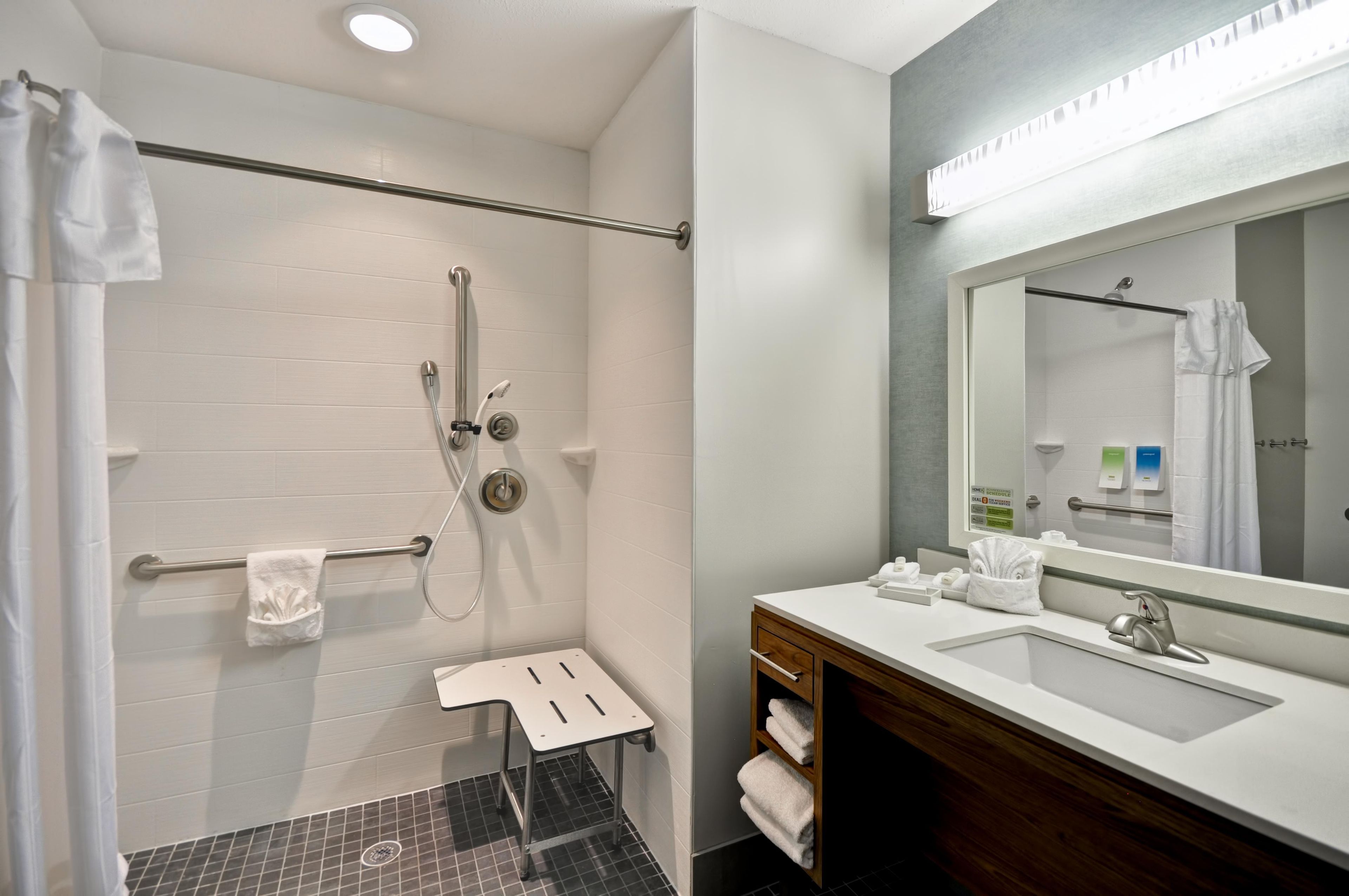 Un baño moderno con ducha, tocador con espejo y un perchero para toallas.