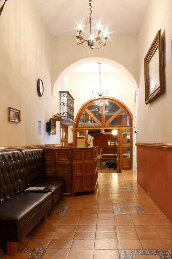 A lobby with a wooden bench, a chandelier, and a large arched doorway leading to another room. - Hotel Santa Fe (Tlatlauquitepec)