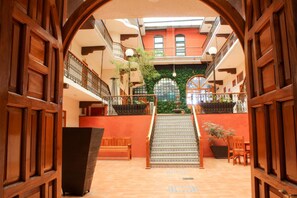 A spacious atrium with a central staircase, wooden doors, and a balcony with plants. - Hotel Santa Fe (Tlatlauquitepec)