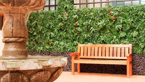 A wooden bench next to a stone fountain with a lush green hedge in the background. - Hotel Santa Fe (Tlatlauquitepec)