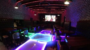 A dimly lit bar with brick walls, neon lights, and a large TV screen. - Hotel Santa Fe (Tlatlauquitepec)