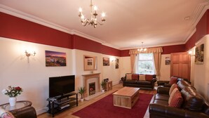 A living room with a fireplace, leather sofas, a TV, and a red carpet. - Spacious stylish house for group stays in  beautiful Buxton, pet friendly.   (Buxton)