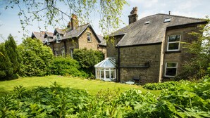 A stone house with a conservatory, surrounded by lush greenery and a well-maintained lawn. - Spacious stylish house for group stays in  beautiful Buxton, pet friendly.   (Buxton)