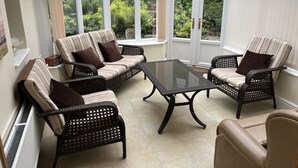 A conservatory with a glass roof, featuring a sofa set, two armchairs, and a glass coffee table. - Spacious stylish house for group stays in  beautiful Buxton, pet friendly.   (Buxton)