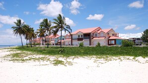 Una propiedad frente a la playa con varias edificaciones, palmeras y una playa de arena.