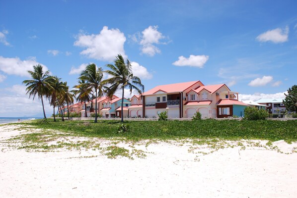A beachfront property with multiple buildings, palm trees, and a sandy beach.