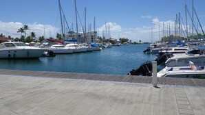 Un puerto deportivo con varias embarcaciones amarradas, una cubierta de madera y un edificio al fondo.