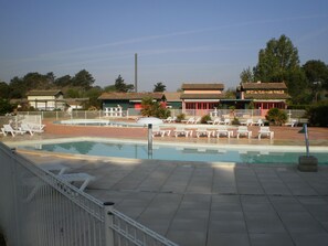Una piscina con sillas de descanso y un edificio tradicional al fondo.