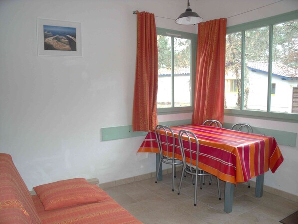 Un comedor con una mesa y sillas, una ventana con cortinas y un cuadro en la pared.