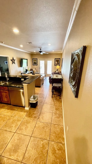 A spacious kitchen with a central island, a dining area with a table and chairs, and a living room with a sofa and a TV.