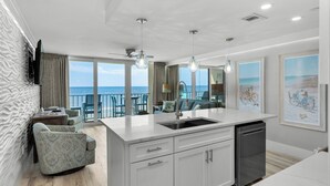 A modern kitchen with a large island, white cabinetry, and a view of the ocean.