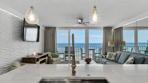 A modern living room with a large window, a ceiling fan, and a view of the ocean.