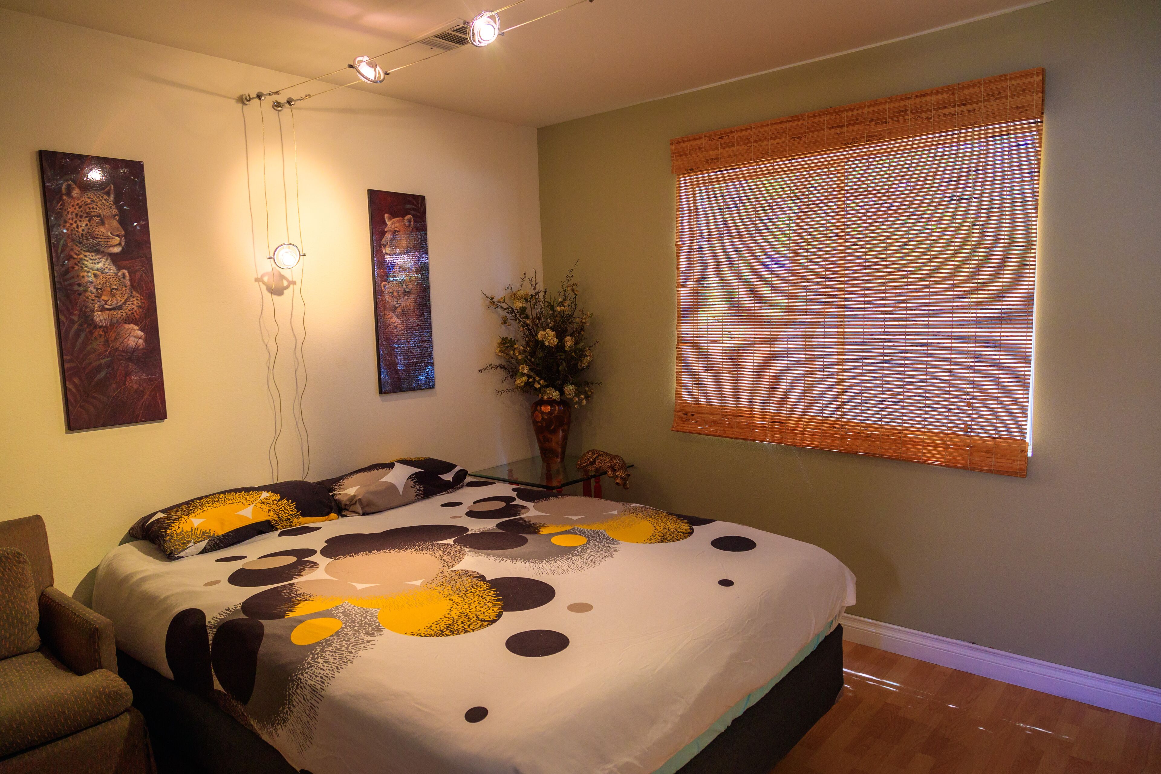 A bedroom with a bed, a chair, a wall-mounted light fixture, and a window with blinds.