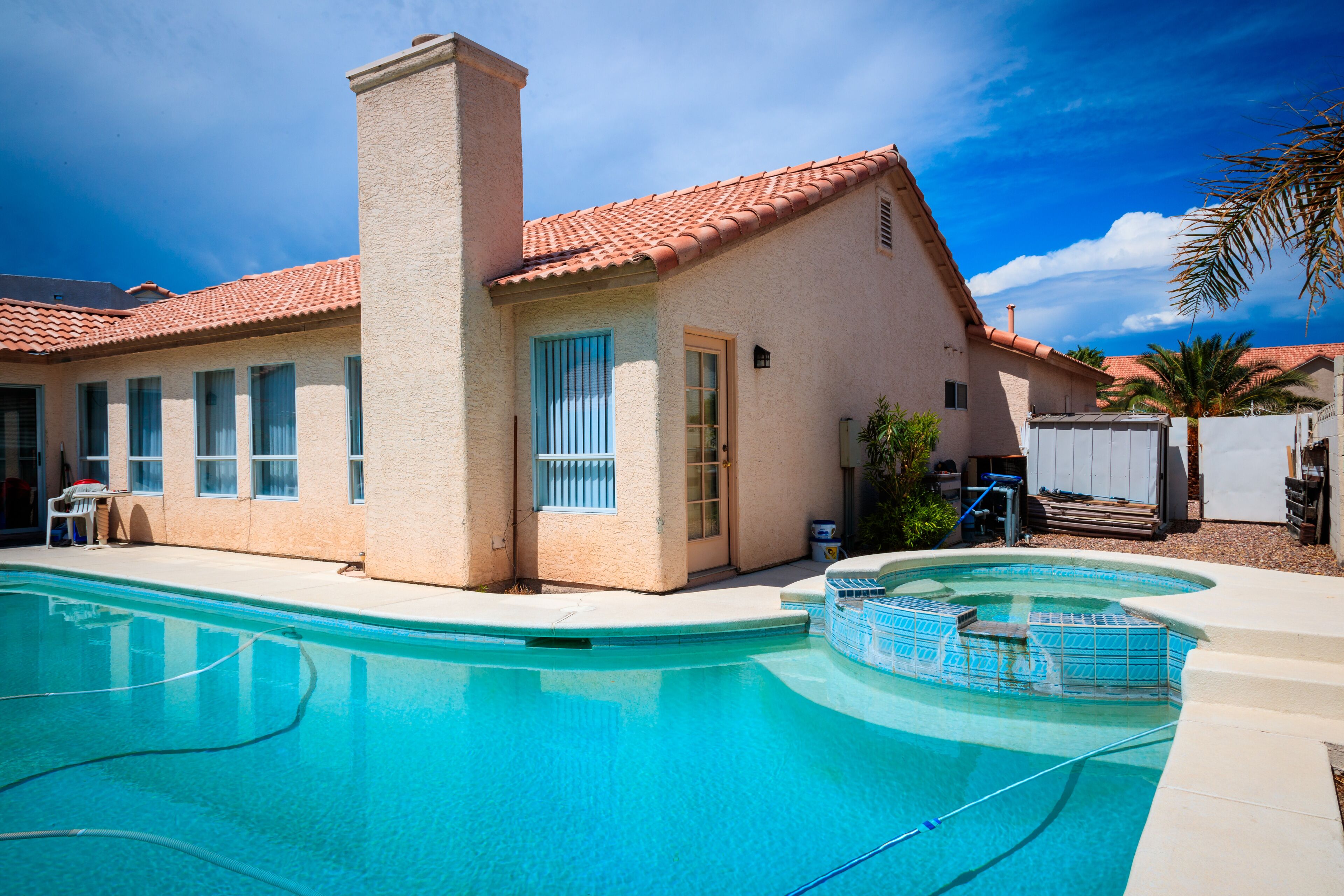 Una casa con piscina, un camino e una porta con una finestra.