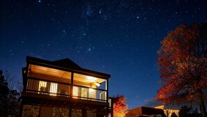 A two-story house with a stone facade, a balcony, and a starry night sky.