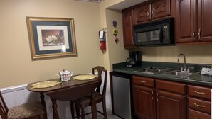 A kitchen with wooden cabinets, a microwave, a sink, and a dining table with chairs.