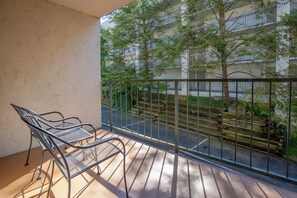 Un balcon avec des chaises en métal et une vue sur un immeuble bordé d’arbres.