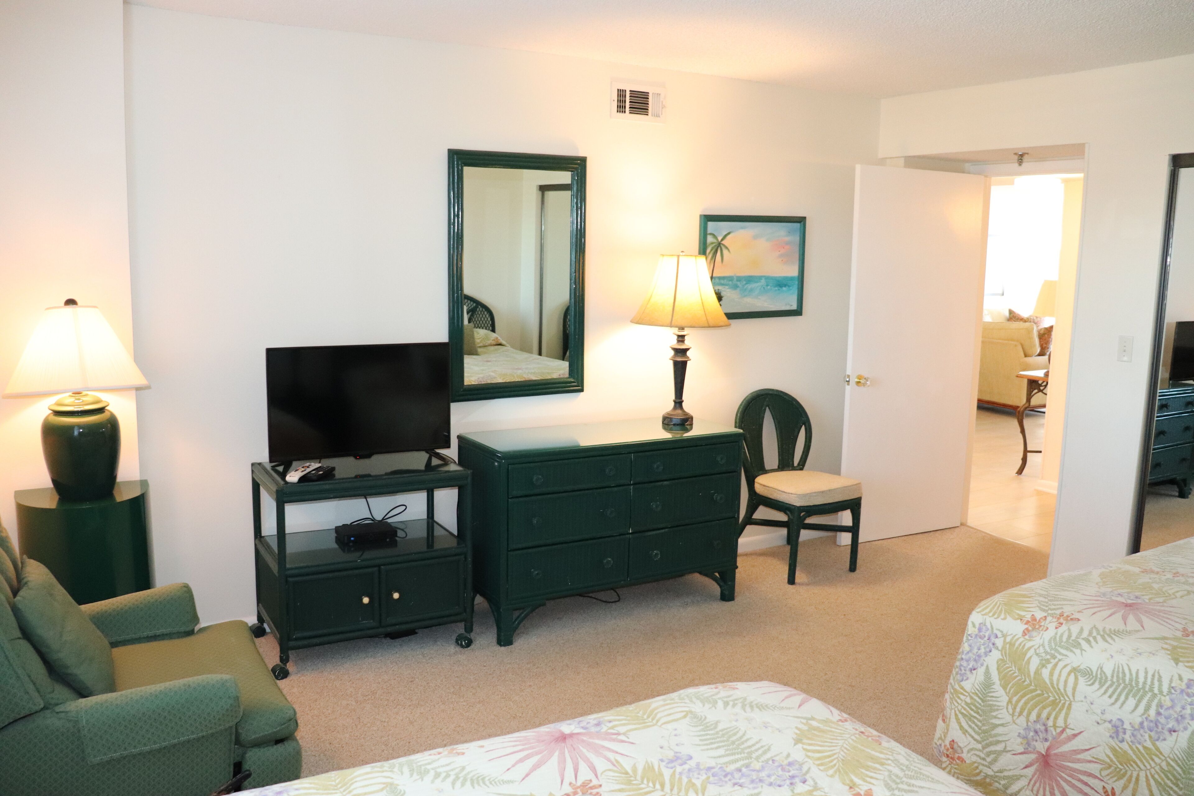 A hotel room with a bed, a TV, a dresser, a chair, and a lamp.