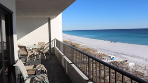 A balcony with outdoor furniture overlooking a beach and ocean. - Surf Dweller 611 by Alicia Hollis Rentals FREE TICKETS & BEACH SERVICE! (Fort Walton Beach)