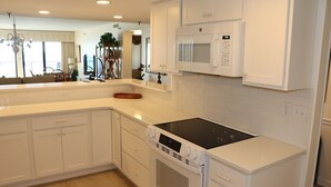 A modern kitchen with white cabinetry, a built-in microwave, an oven, and a dishwasher. - Surf Dweller 611 by Alicia Hollis Rentals FREE TICKETS & BEACH SERVICE! (Fort Walton Beach)