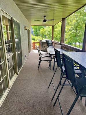Veranda coperta con tavolo e sedie, ventilatore a soffitto e vista sul verde.