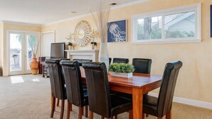 A dining area with a wooden table and black chairs, a fireplace, and a large window.