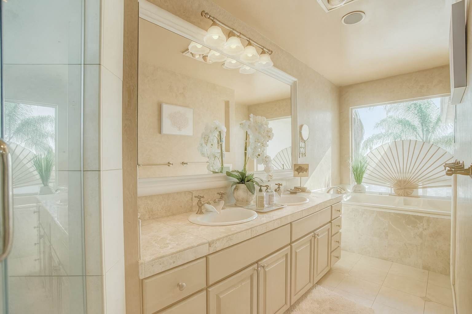 A modern bathroom with a large mirror, two sinks, and a vanity with drawers.