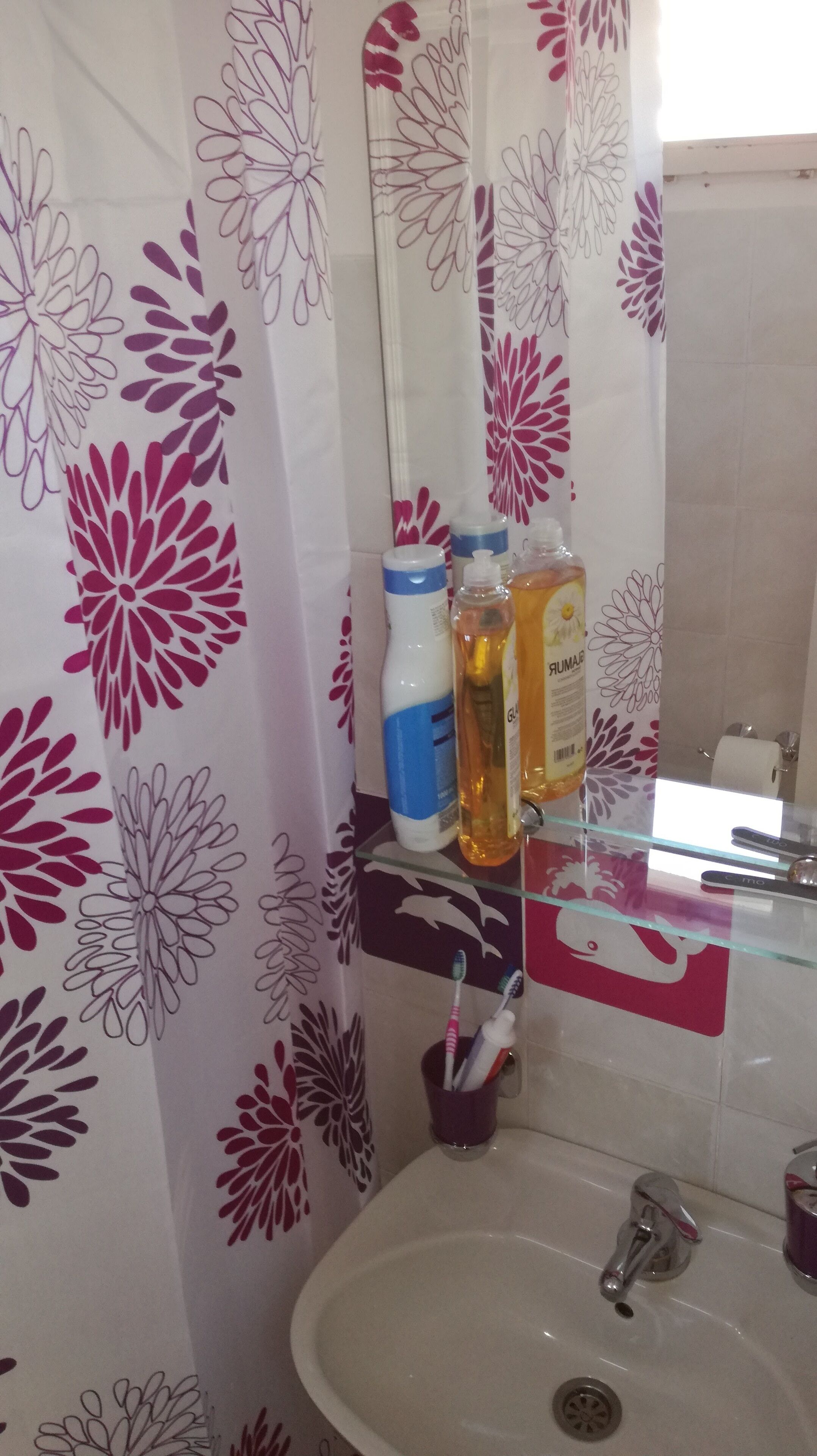 Un bany amb un lavabo, estelles de dent i una petita estanteria de vidre amb productes de tocador.
