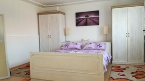 Un dormitorio con una cama, dos armarios, una mesita de noche, una lámpara y un cuadro en la pared.