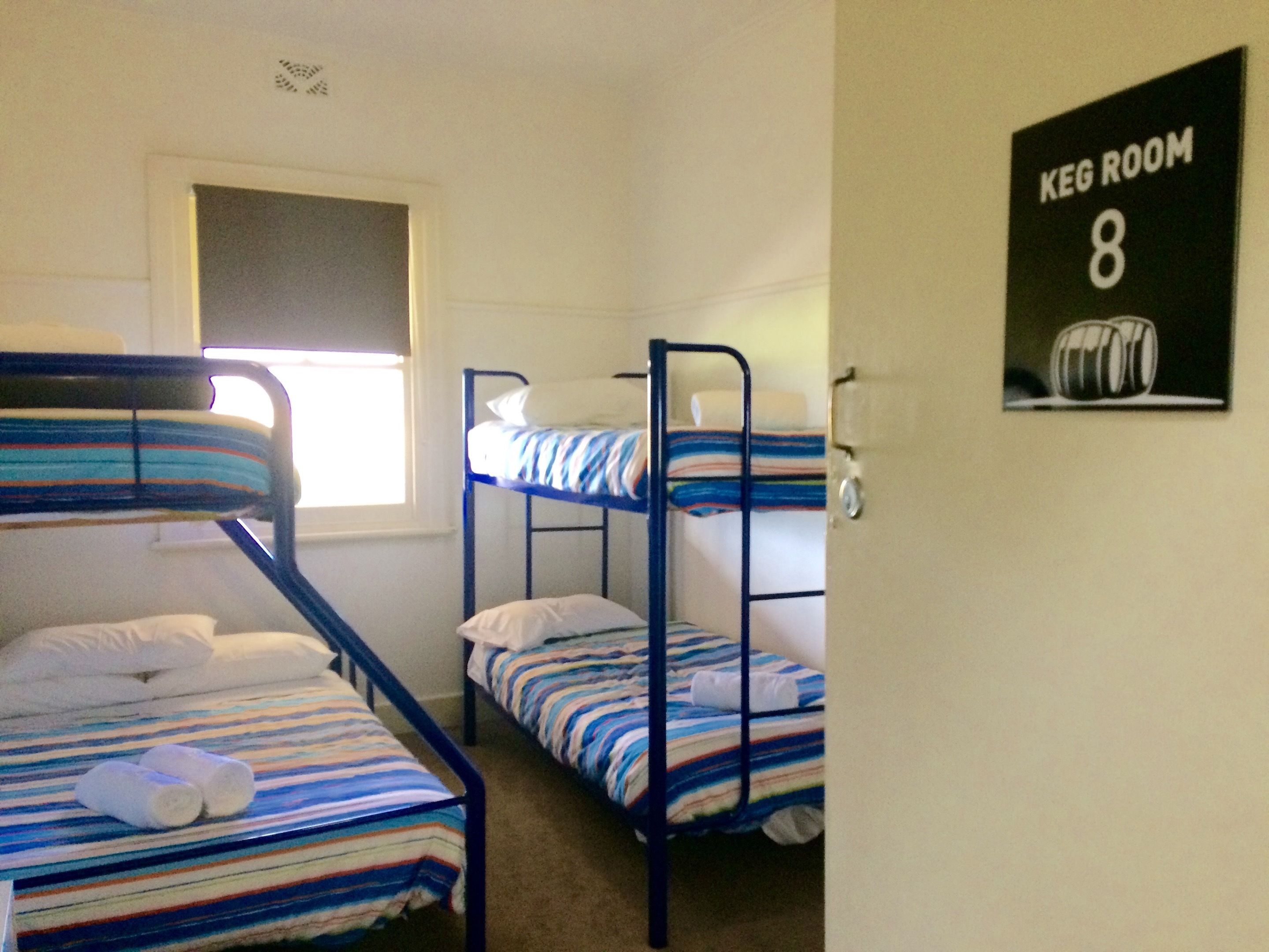 A dormitory room with bunk beds, a window, and a poster on the wall.