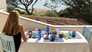 Ein Tisch mit verschiedenen Gegenständen, mit Blick auf eine Küstenlandschaft mit Bäumen und einer felsigen Uferlinie.