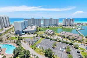 A hotel with multiple buildings, a swimming pool, parking area, and a view of the ocean. - Luxury 16th Floor Condo with Breathtaking View! NEW FURNITURE! (Miramar Beach)