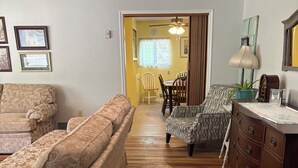 A room with a patterned sofa, a wooden dresser, a dining area with chairs, and a chandelier. - Zion and Bryce Canyon Getaway (Glendale)